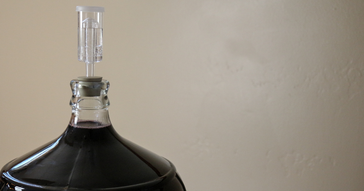 carboy of dark beer with airlock